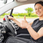 Car. Beautiful woman in the car shows thumbs up. Happy brunette in the car.