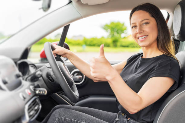 Car. Beautiful woman in the car shows thumbs up. Happy brunette in the car.